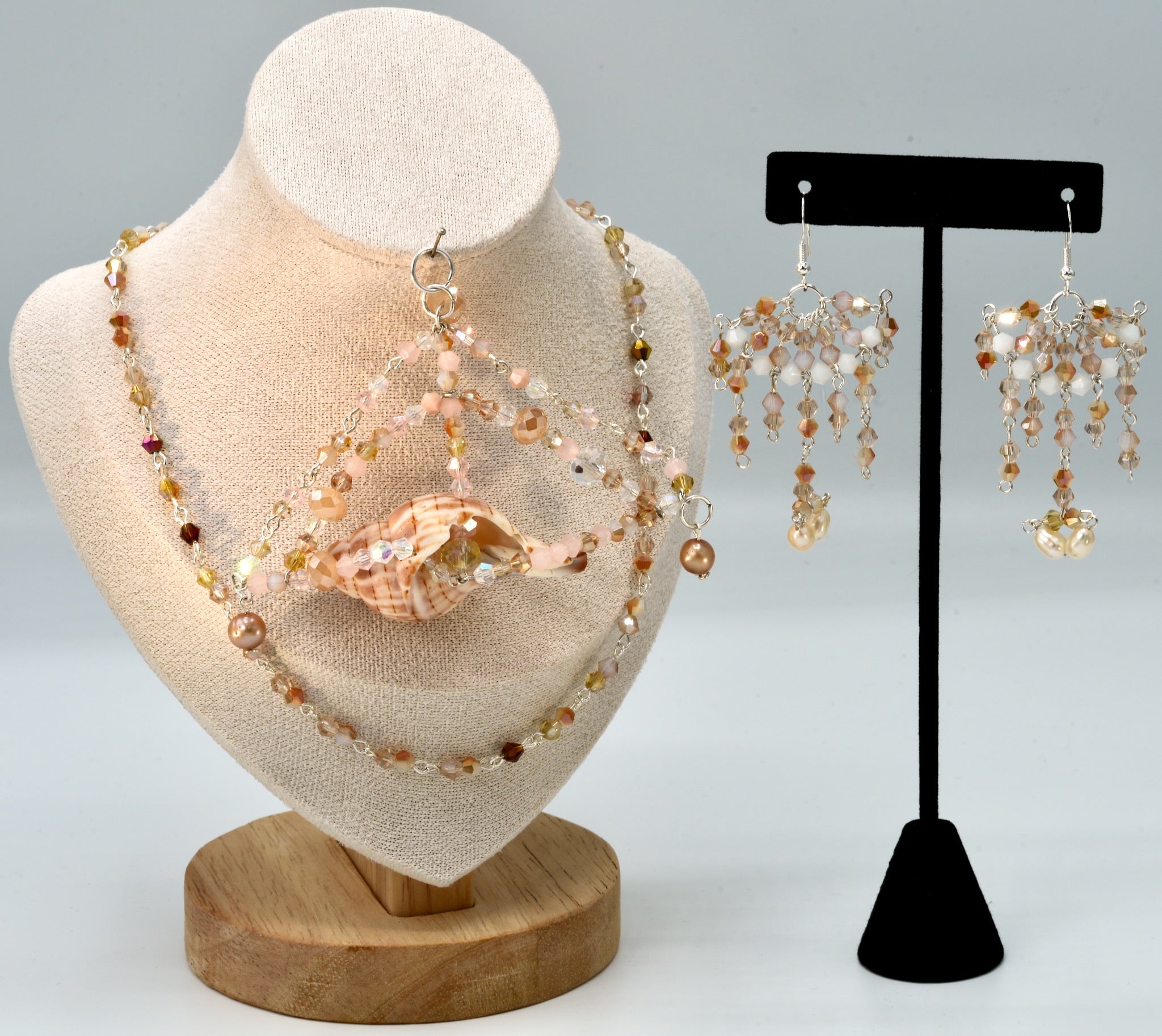 Jewelry set including necklace and earrings on a mannequin and stand.