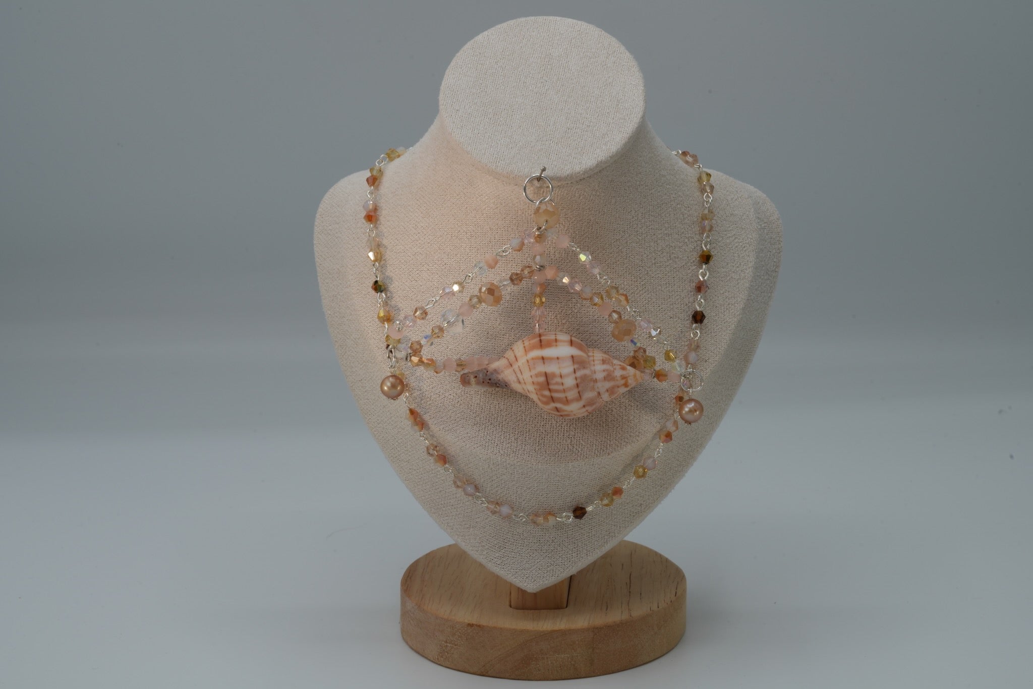 Necklace with seashells on a mannequin bust against a gray background