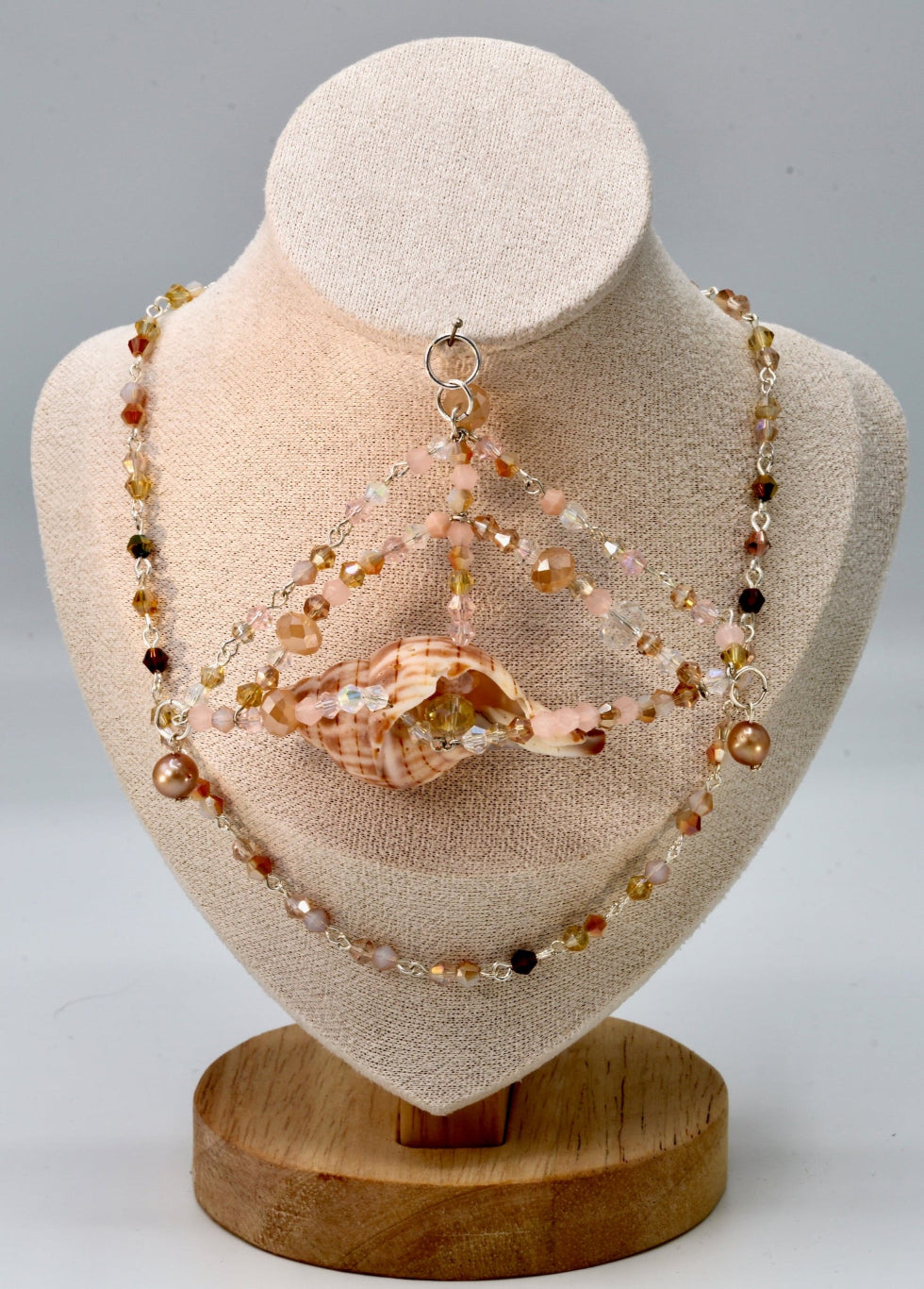 Jewelry set with beads and a shell on a mannequin bust.